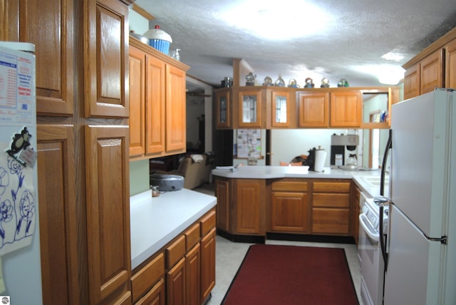 kitchen featuring kitchen peninsula, white appliances, and a textured ceiling