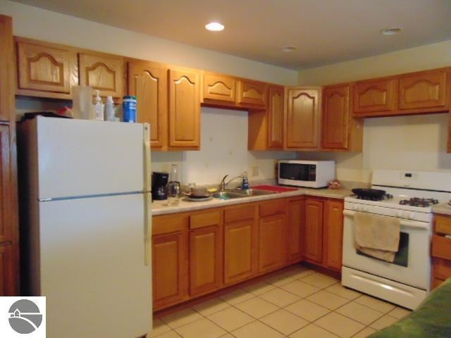 kitchen with sink, white appliances, and light tile patterned flooring