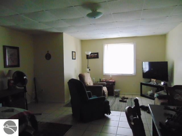 tiled living room with a paneled ceiling