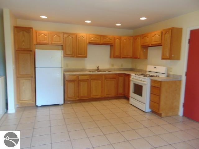 kitchen with light tile patterned floors, sink, and white appliances