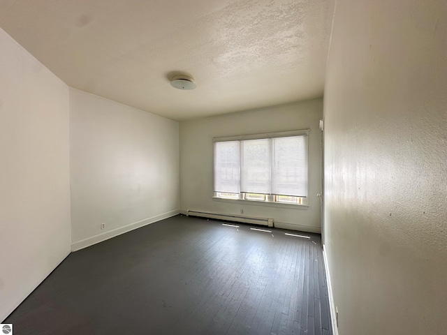 empty room featuring dark hardwood / wood-style floors, baseboard heating, and a textured ceiling