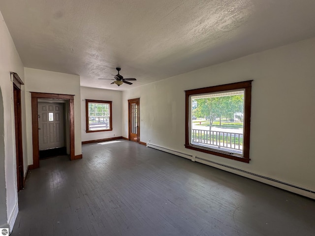 unfurnished room with dark wood-type flooring, baseboard heating, a wealth of natural light, and ceiling fan