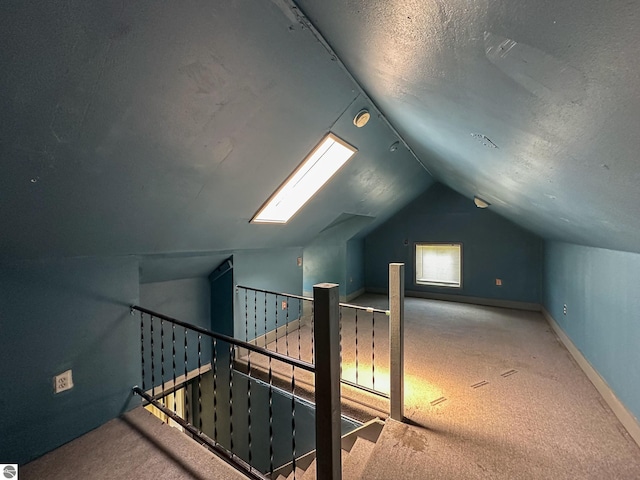 bonus room featuring carpet flooring, vaulted ceiling with skylight, and a textured ceiling