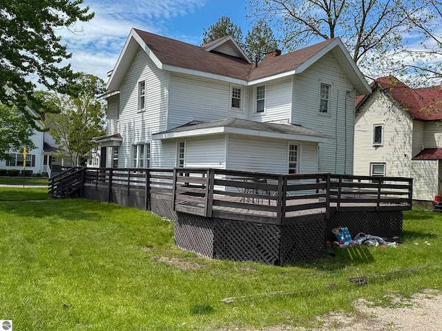 rear view of property with a wooden deck and a lawn