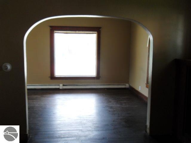 spare room with dark hardwood / wood-style floors and a baseboard radiator