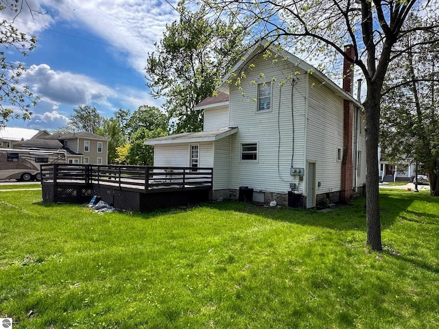 back of property with a deck and a yard