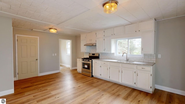 kitchen featuring sink, stainless steel gas range, white cabinets, and light hardwood / wood-style flooring