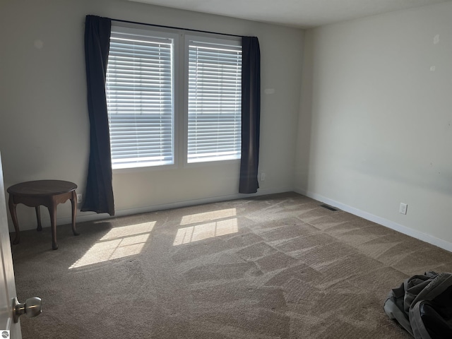 carpeted spare room featuring visible vents and baseboards