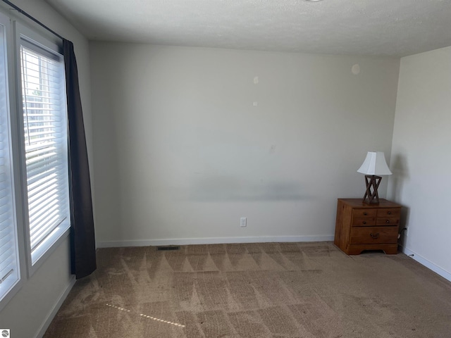 carpeted empty room with a textured ceiling