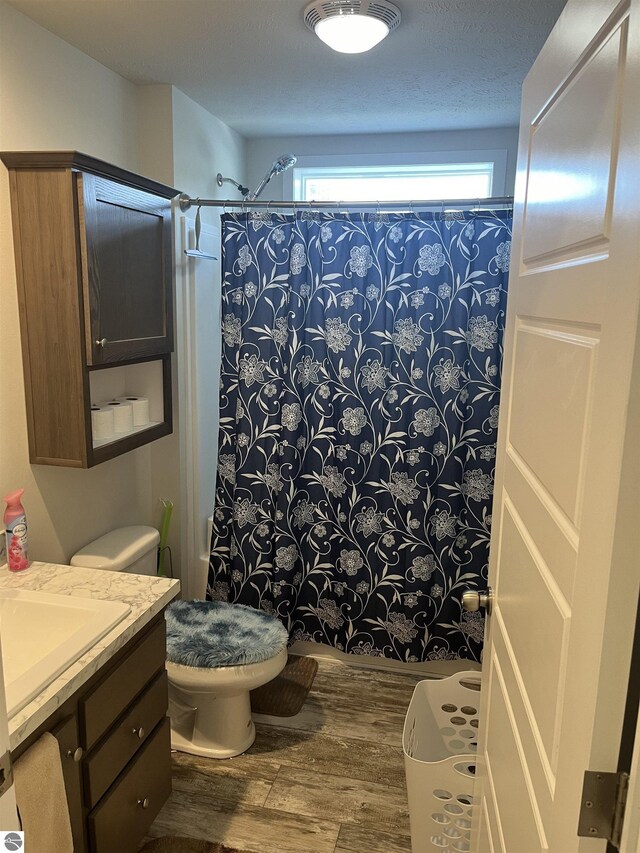 full bathroom with vanity, shower / bathtub combination with curtain, wood-type flooring, and toilet