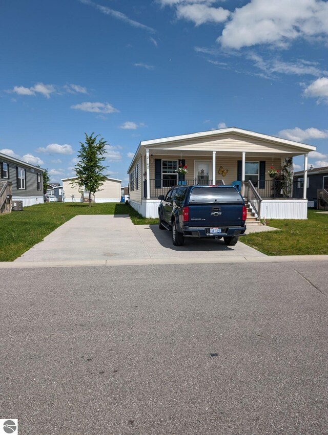 manufactured / mobile home featuring a porch and a front lawn