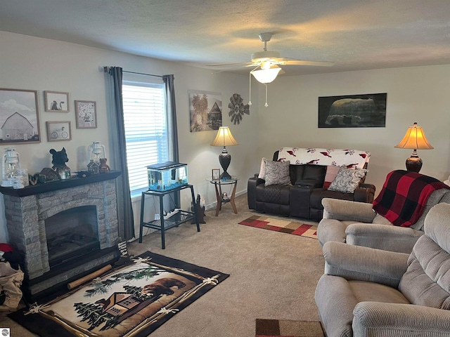 living room with a stone fireplace, carpet, and ceiling fan