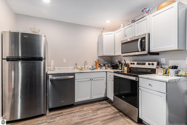 812 Forest Ave, Frankfort, MI 49635 - kitchen featuring stainless steel appliances, wood-type flooring, and white cabinetry