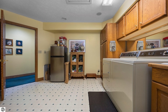 laundry area featuring cabinets, a textured ceiling, light tile floors, and washing machine and clothes dryer