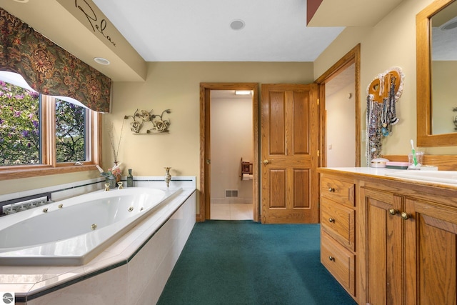 bathroom with tile flooring, tiled tub, and vanity