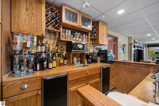 bar with black dishwasher, a paneled ceiling, and butcher block countertops