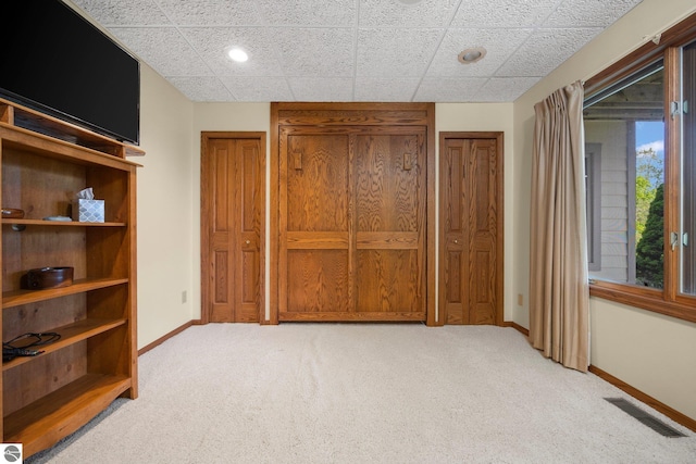 carpeted bedroom featuring two closets and a paneled ceiling