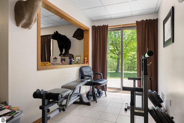 workout area featuring light tile flooring and a drop ceiling