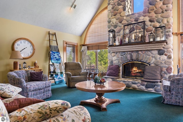 living room featuring a stone fireplace, high vaulted ceiling, track lighting, and carpet