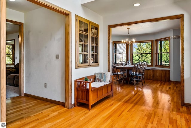 unfurnished dining area with a notable chandelier and light wood-type flooring