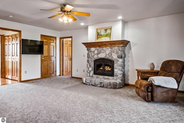 carpeted living room with a fireplace and ceiling fan