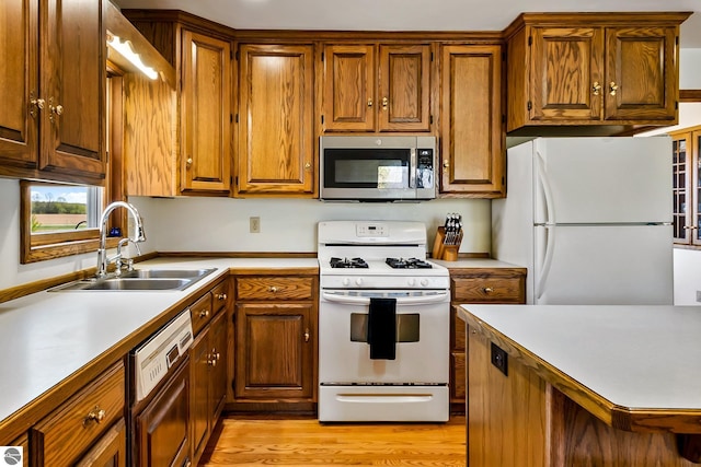 kitchen with sink, white appliances, and light wood-type flooring