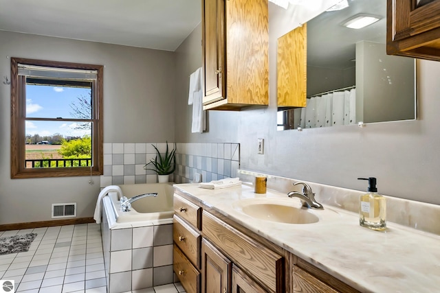 bathroom featuring tile patterned floors, vanity, and tiled tub