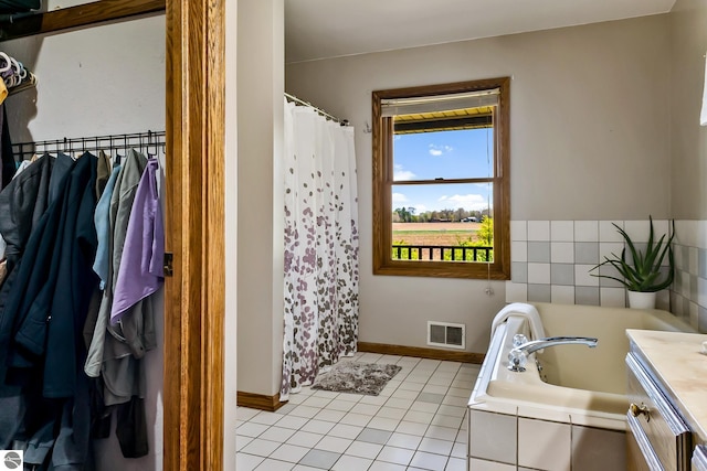 bathroom featuring tiled bath, tile patterned flooring, and vanity