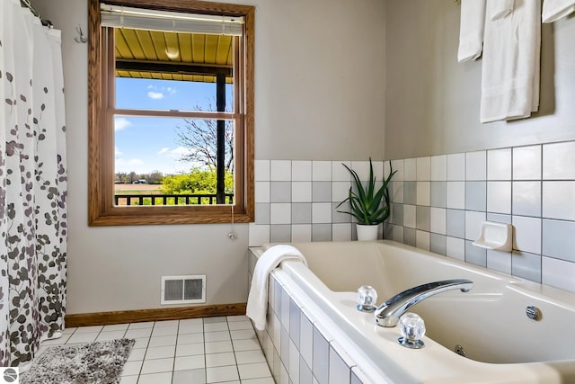 bathroom with tiled tub and tile patterned flooring