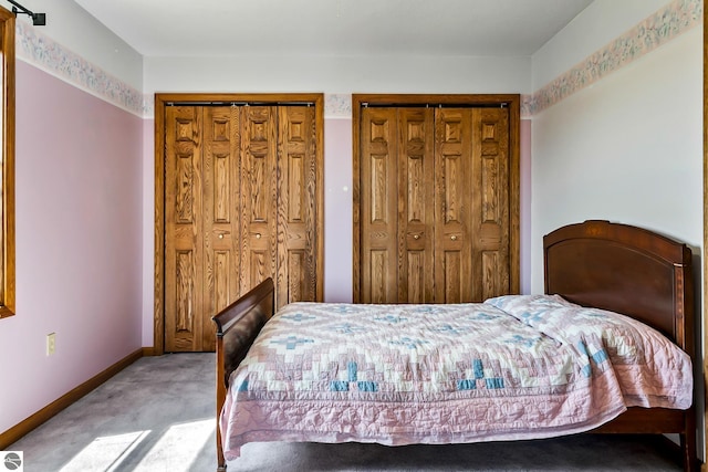 bedroom featuring light colored carpet and multiple closets