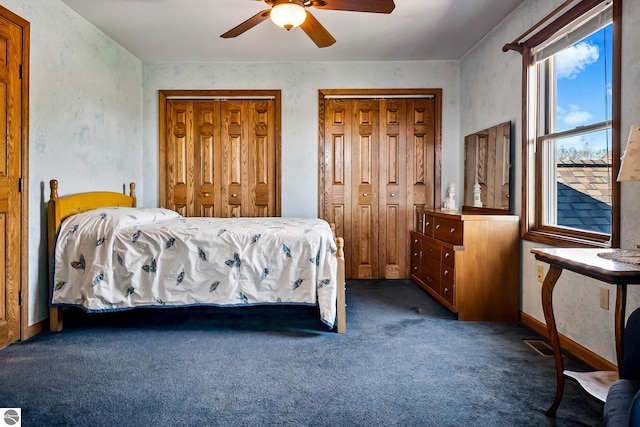 carpeted bedroom featuring ceiling fan and multiple closets