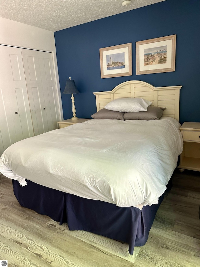 bedroom with a textured ceiling, a closet, and hardwood / wood-style floors