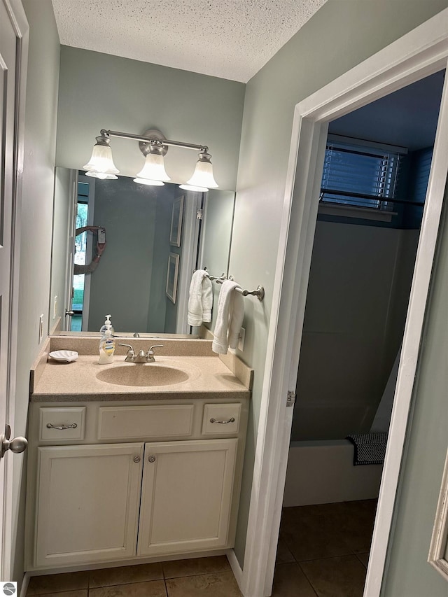 bathroom with a washtub, a textured ceiling, vanity, and tile patterned flooring