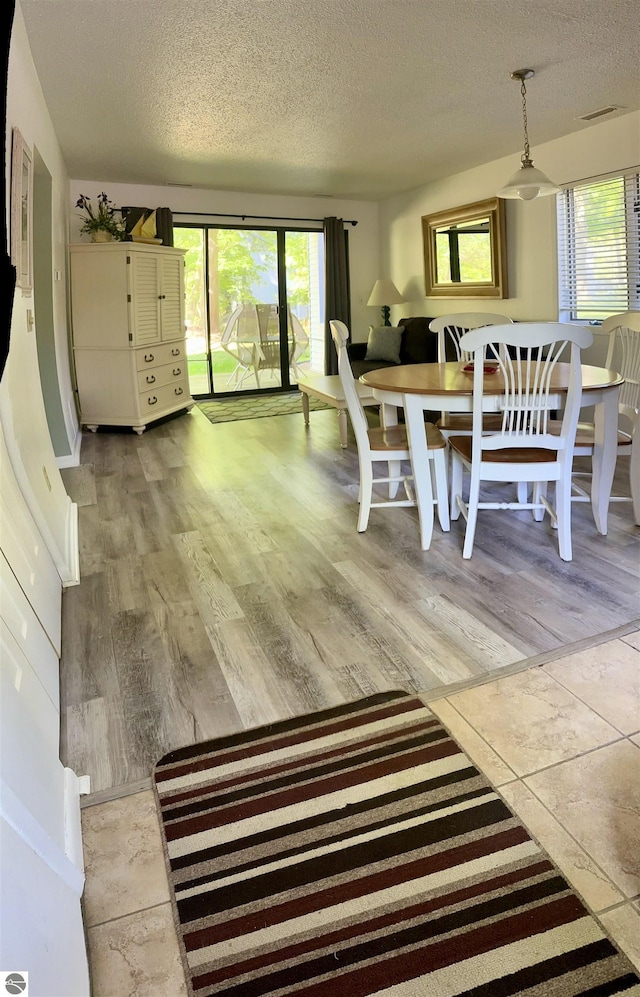 unfurnished dining area featuring a textured ceiling and light wood-type flooring