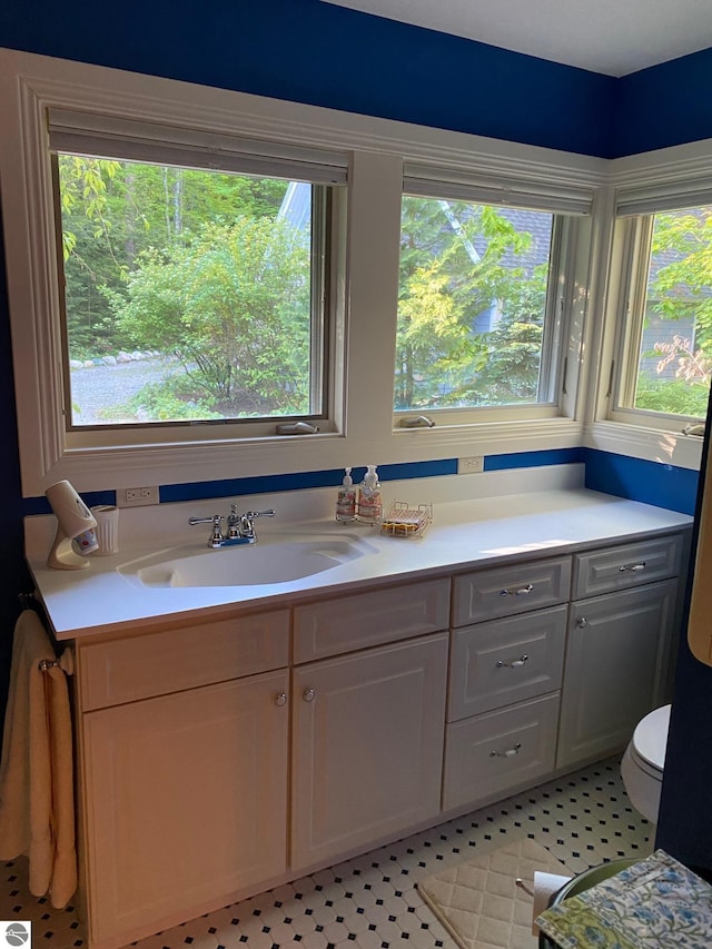 bathroom featuring tile flooring, a wealth of natural light, toilet, and vanity