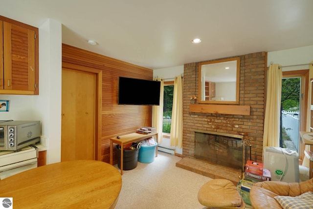 living room with a wealth of natural light, brick wall, a brick fireplace, and baseboard heating