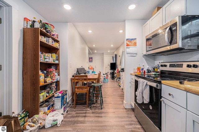 kitchen with stainless steel appliances, white cabinets, and hardwood / wood-style flooring