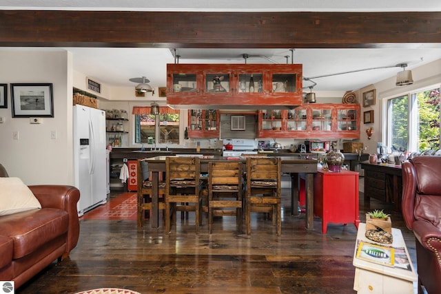 kitchen with beamed ceiling, white appliances, sink, and dark hardwood / wood-style floors