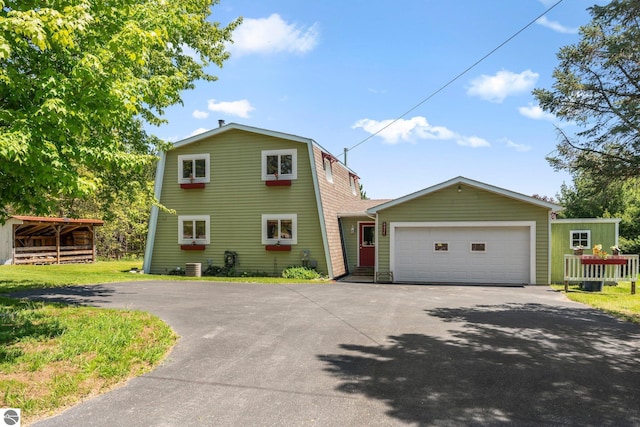 view of front of property with a front yard, an outdoor structure, central air condition unit, and a garage