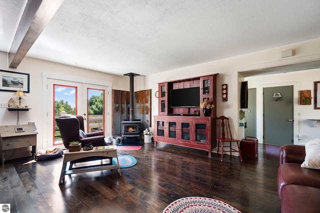 living room with dark hardwood / wood-style floors, beam ceiling, a textured ceiling, and a wood stove