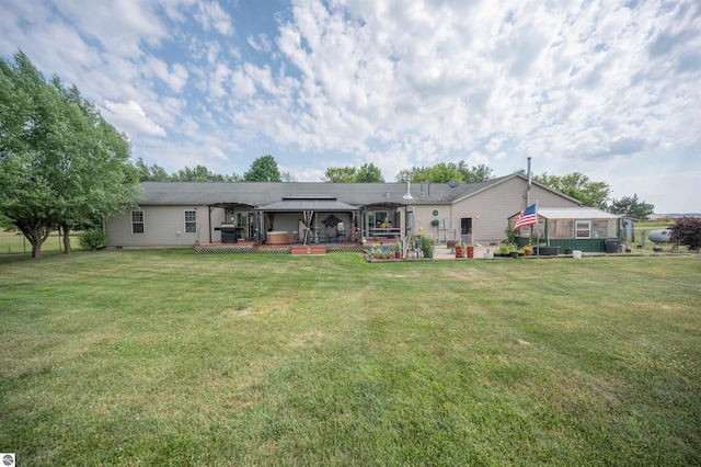 rear view of property with a gazebo, a deck, and a yard