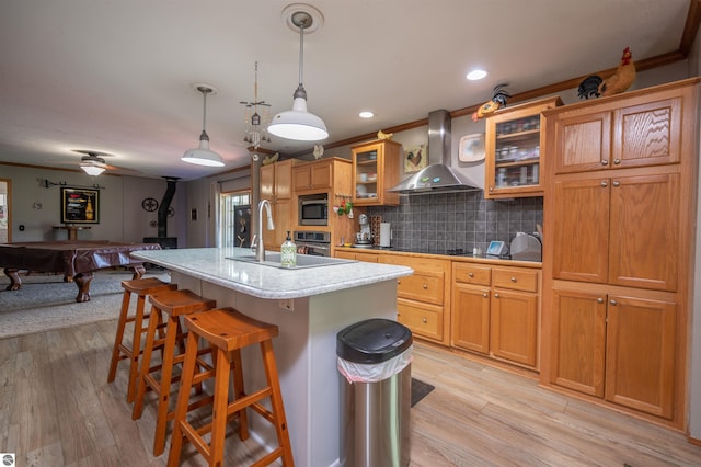 kitchen with pool table, a kitchen island with sink, crown molding, and wall chimney range hood