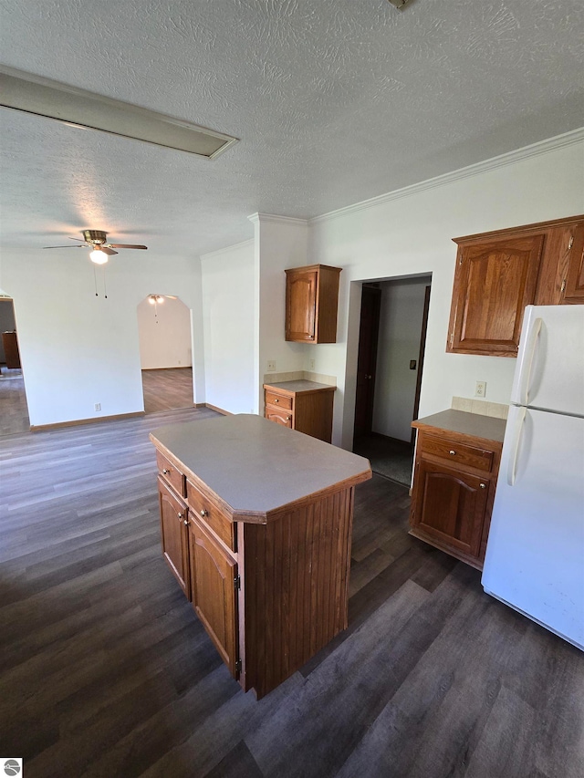 kitchen featuring white refrigerator, dark hardwood / wood-style floors, ceiling fan, a center island, and a textured ceiling