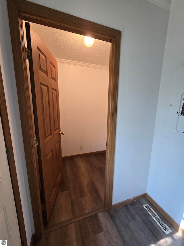 hall featuring dark hardwood / wood-style floors, ornamental molding, and a textured ceiling