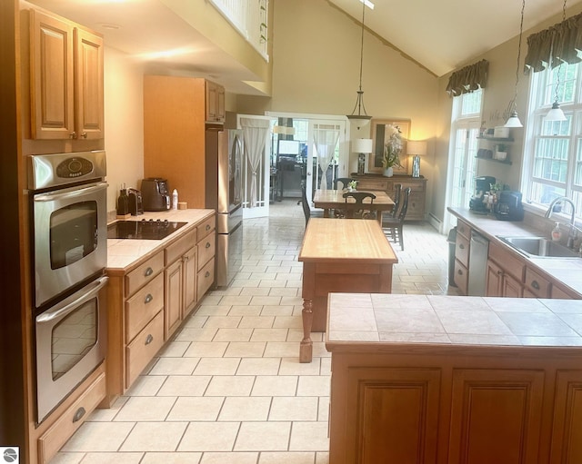 kitchen featuring stainless steel appliances, sink, decorative light fixtures, a kitchen island, and lofted ceiling