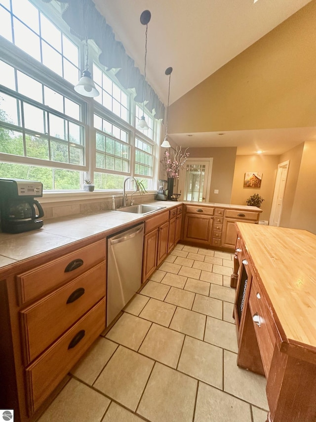 kitchen featuring sink, hanging light fixtures, stainless steel dishwasher, butcher block countertops, and light tile patterned flooring