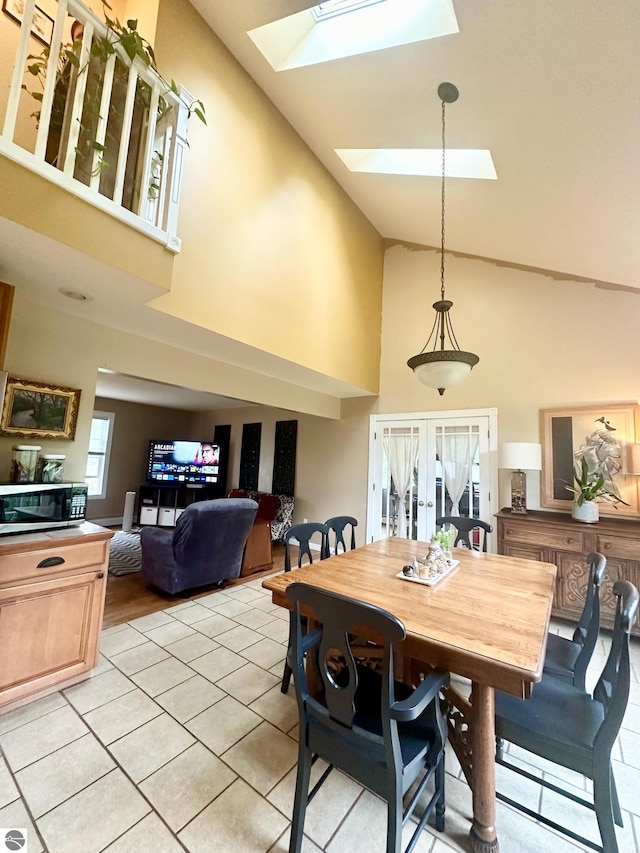 tiled dining room with a skylight, french doors, and high vaulted ceiling