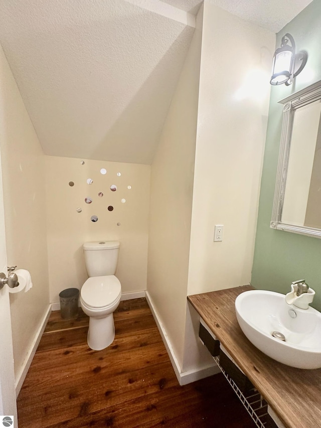 bathroom featuring vanity, a textured ceiling, wood-type flooring, toilet, and lofted ceiling