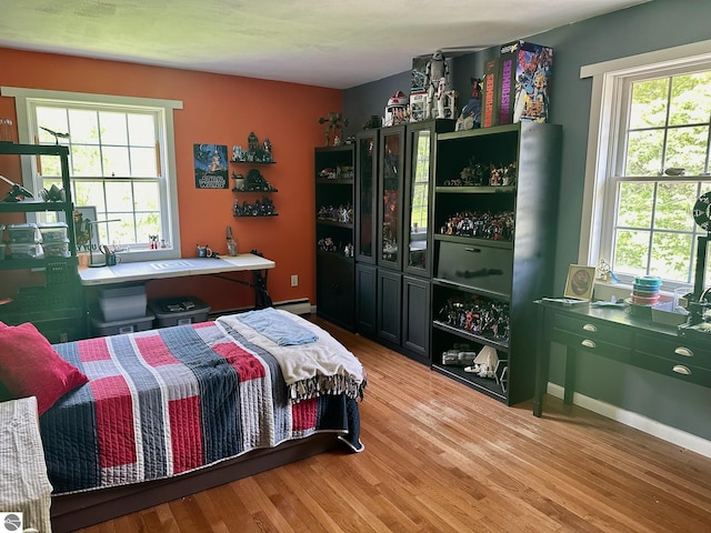 bedroom with light wood-type flooring and a baseboard heating unit