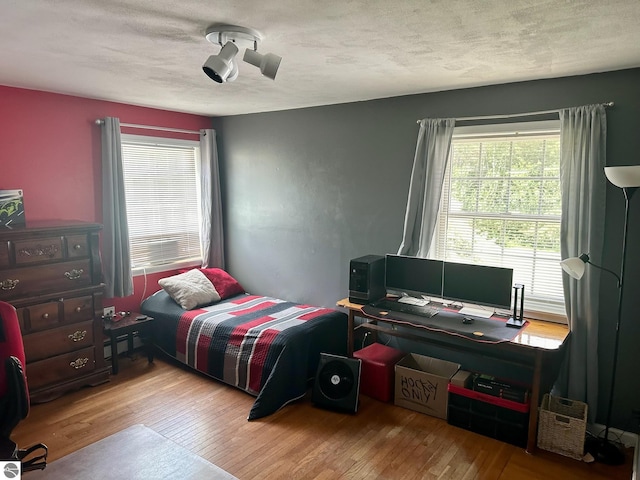 bedroom with multiple windows, light wood-type flooring, and ceiling fan